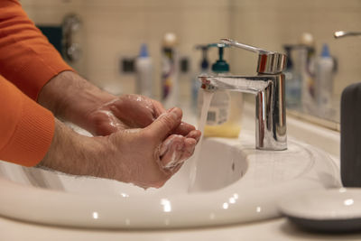 Global handwashing day concept. washing hands with soap under the water tap with water in bathroom.