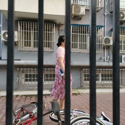 Rear view of man walking on street against building