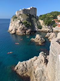 Scenic view of sea and rocks against clear blue sky