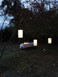 Empty seats on table against trees at dusk