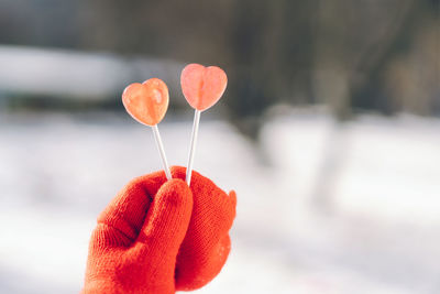 Valentines day card. woman in red mittens holding two heart shaped lollipops. i love you