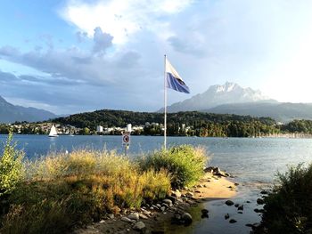 Scenic view of flag by lake against sky