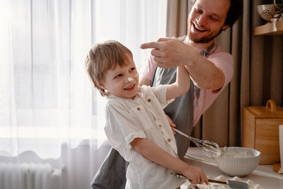 Dad holds a blender and plays with his little son.  the boy laughs and turns away. family fun 