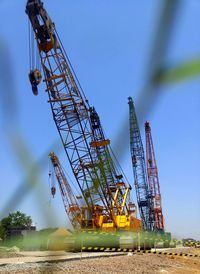 Low angle view of cranes against blue sky