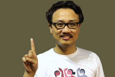 Portrait of young man standing against black background