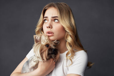 Portrait of woman with dog against black background