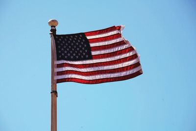 Low angle view of american flag against blue sky