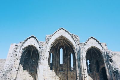 Low angle view of old ruins against clear blue sky