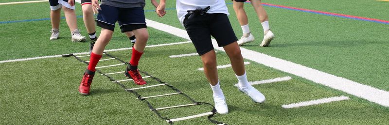 Young football players at summer training camp running in the ladder drill