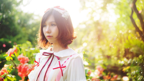 Portrait of young woman standing against plants