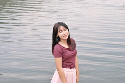 Portrait of smiling young woman standing in water