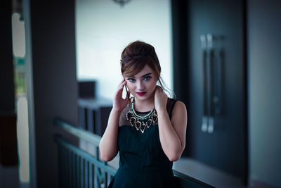 Portrait of young woman standing against wall