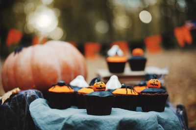 Close-up of cupcakes and pumpkin on table during halloween celebration