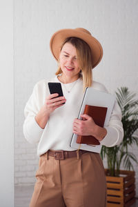 Trendy woman wearing brown hat using smartphone 