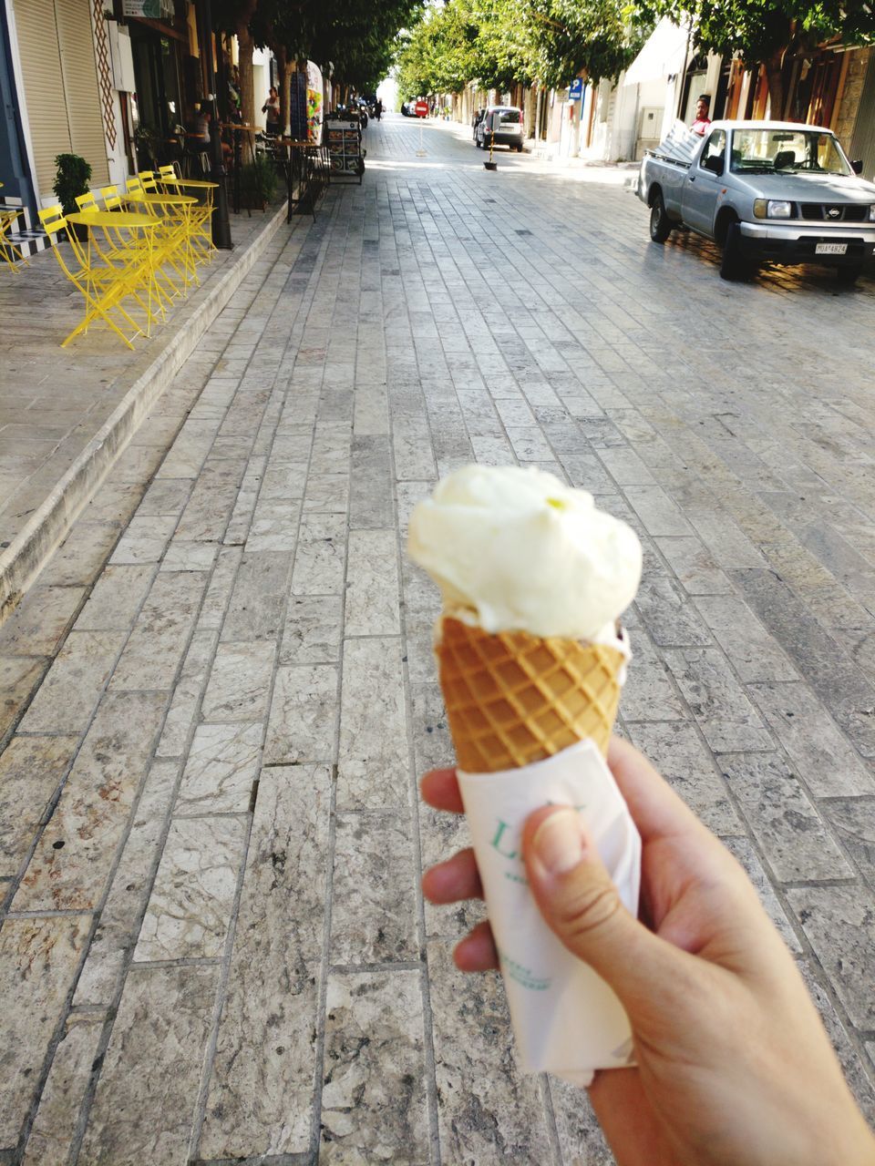 HAND HOLDING ICE CREAM CONE ON TABLE