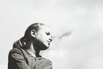 Close-up of young girl against sky