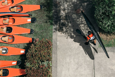 High angle view of man carrying kayak and oar on footpath