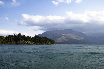 Scenic view of sea by mountains against sky