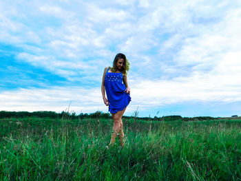 Full length portrait of young woman standing on field