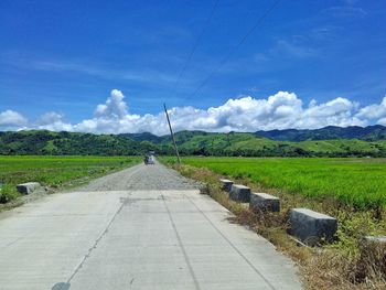 Road amidst field against sky