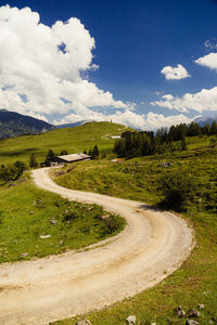 Road amidst field against sky