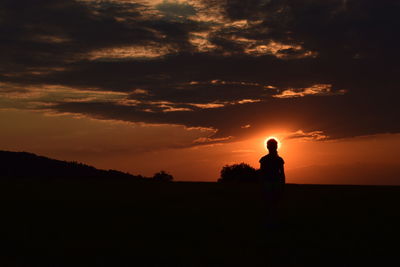Silhouette man standing against orange sky