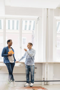 Full length of computer programmers standing by window in office