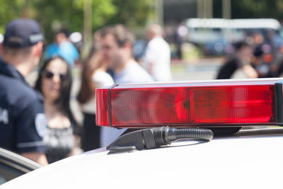 Close-up of police car with people in background