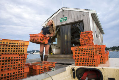 Female shellfish farmer carrying orange crates of oysters