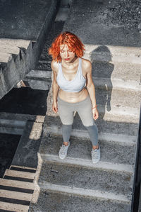 Woman in running gear, crop top and shorts, stretching her body and preparing for a run, or cooling