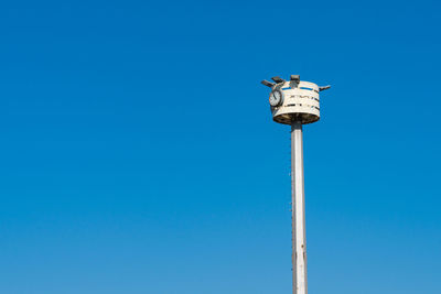 Tall clock pole against clear blue sky during bright daytime