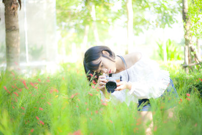Young woman photographing plants at park