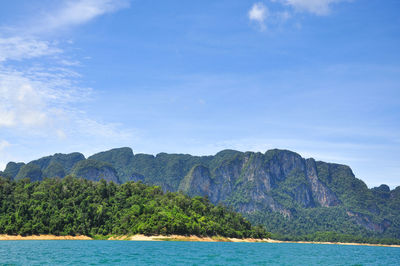 Scenic view of mountain by sea against blue sky