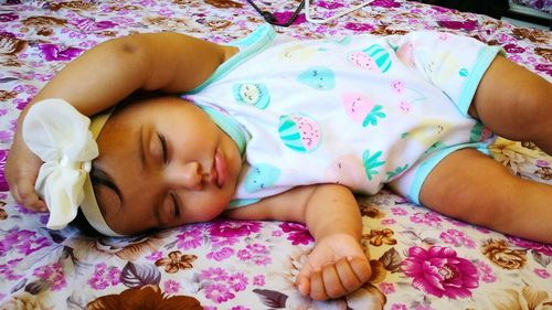 High angle view of baby girl sleeping on bed