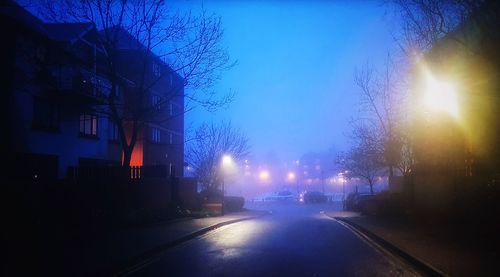 Road passing through illuminated city at night