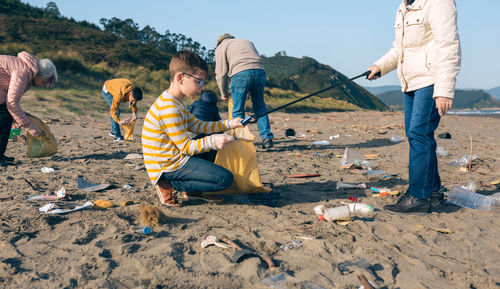 Grandmother and grandson with group of volunteers picking up trash on the beach