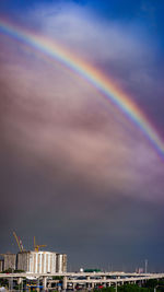 Low angle view of rainbow over buildings against sky