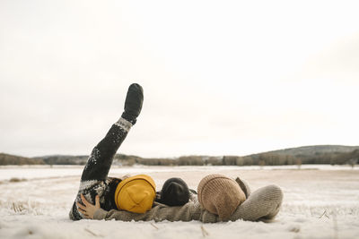 Lesbian mothers with daughter lying on snow during sunset