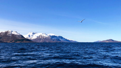 Scenic view of sea and mountains against blue sky