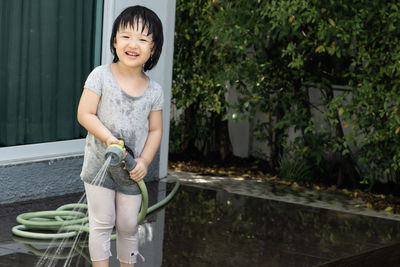 Full length of a smiling young woman standing against plants