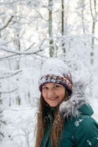 Portrait of young woman standing in forest during winter