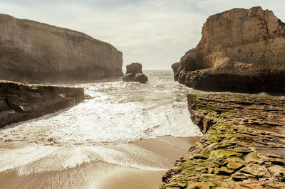 Rock formations on beach against sky