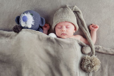 Directly above shot of cute baby boy with stuffed toy sleeping on bed