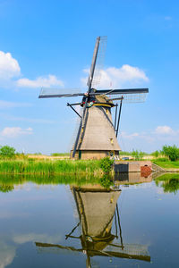 Traditional windmill on lake against sky