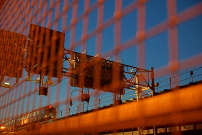 Railway bridge seen through metal grate at night