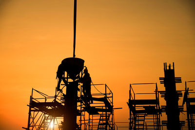 Low angle view of silhouette man standing against orange sky