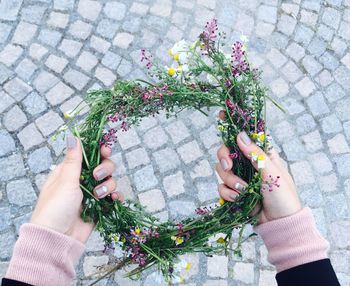 Cropped hands of woman holding wreath over street