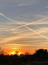 Scenic view of vapor trails in sky at sunset