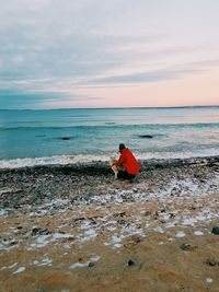 Person and dog by sea against sky