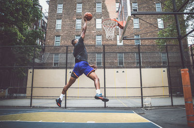 Young man scoring goal at basketball court